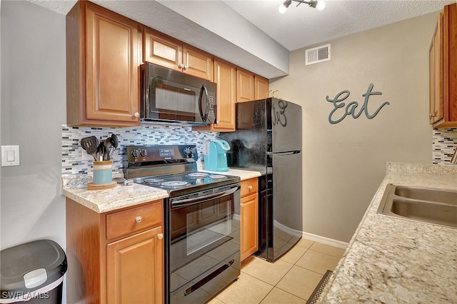 kitchen featuring tasteful backsplash, a textured ceiling, sink, black appliances, and light tile patterned flooring