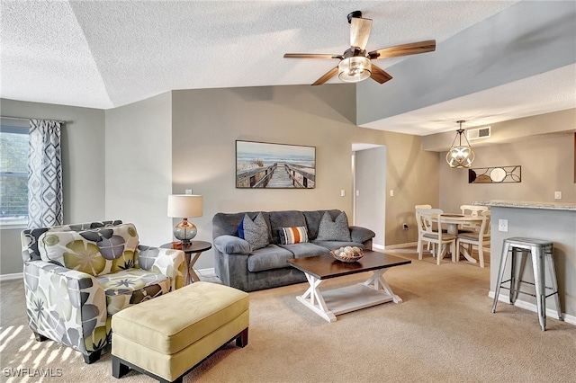 living room with ceiling fan, light colored carpet, a textured ceiling, and vaulted ceiling