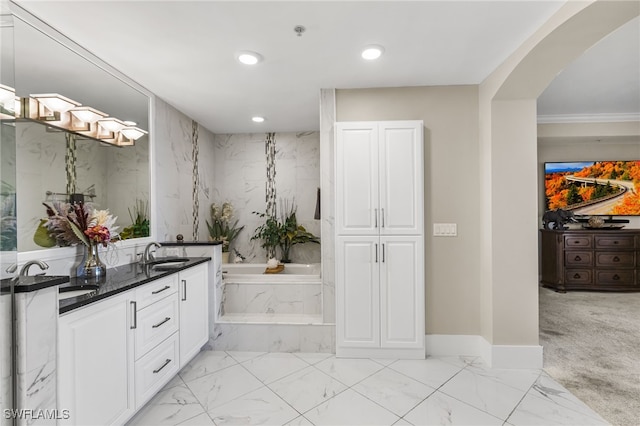 bathroom with tiled bath, crown molding, and vanity