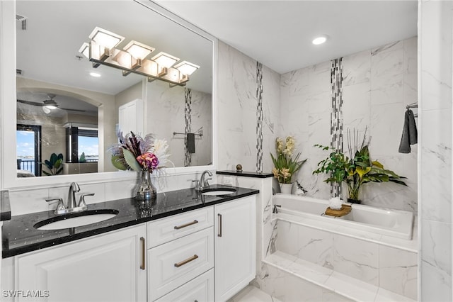 bathroom featuring vanity, ceiling fan, and a relaxing tiled tub