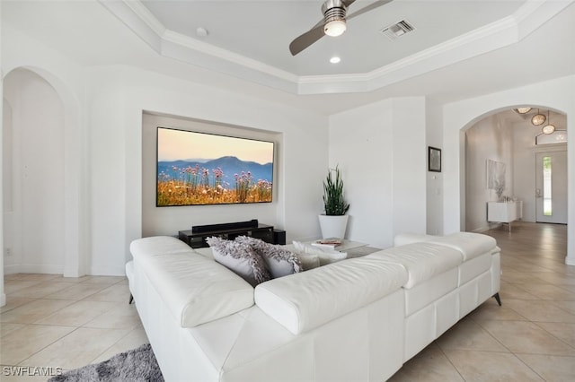 living room featuring ornamental molding, ceiling fan, a tray ceiling, and light tile patterned floors