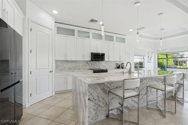 kitchen with pendant lighting, refrigerator, and an island with sink