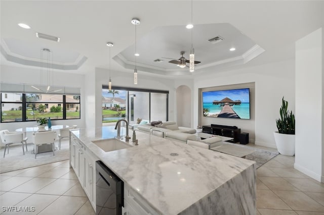 kitchen featuring white cabinets, a raised ceiling, stainless steel dishwasher, sink, and decorative light fixtures