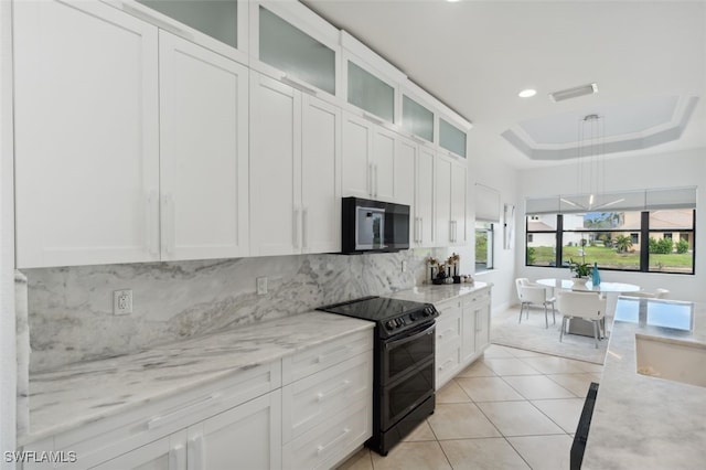 kitchen featuring black electric range, white cabinetry, light stone counters, and a tray ceiling