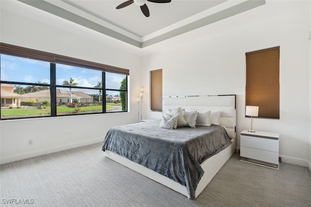 carpeted bedroom featuring ceiling fan and a tray ceiling