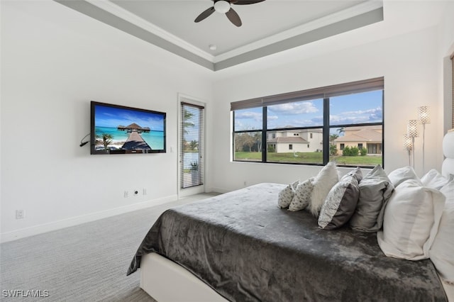 bedroom featuring ceiling fan, a tray ceiling, ornamental molding, and carpet floors