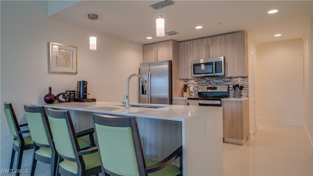 kitchen featuring tasteful backsplash, stainless steel appliances, pendant lighting, light brown cabinets, and light tile patterned floors