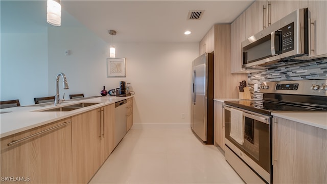 kitchen featuring sink, light brown cabinets, hanging light fixtures, decorative backsplash, and appliances with stainless steel finishes