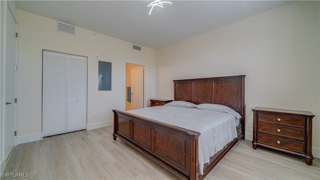 bedroom with electric panel, a closet, and light hardwood / wood-style flooring