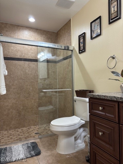 bathroom featuring vanity, a shower with shower door, toilet, and tile patterned flooring