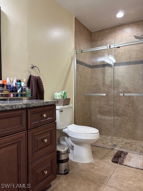 bathroom featuring vanity, tile patterned flooring, toilet, and walk in shower