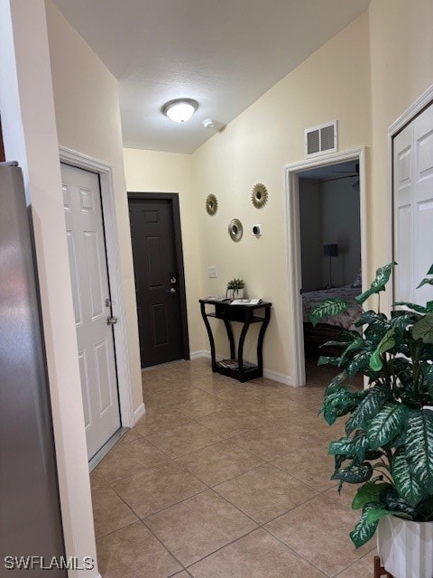 corridor featuring light tile patterned flooring and lofted ceiling