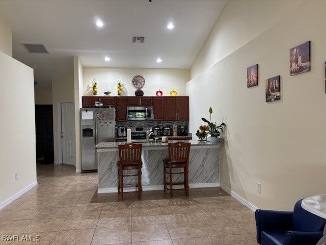 kitchen featuring stainless steel appliances, lofted ceiling, light tile patterned floors, and a kitchen breakfast bar