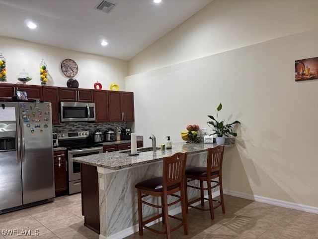 kitchen featuring appliances with stainless steel finishes, sink, kitchen peninsula, lofted ceiling, and a breakfast bar area