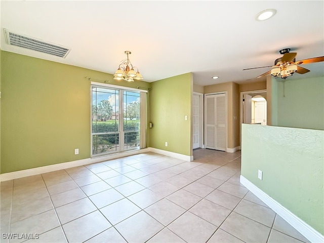 spare room featuring light tile patterned floors and ceiling fan with notable chandelier