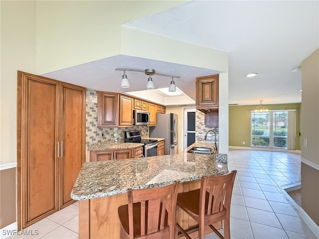 kitchen with kitchen peninsula, tasteful backsplash, a breakfast bar area, sink, and stainless steel appliances