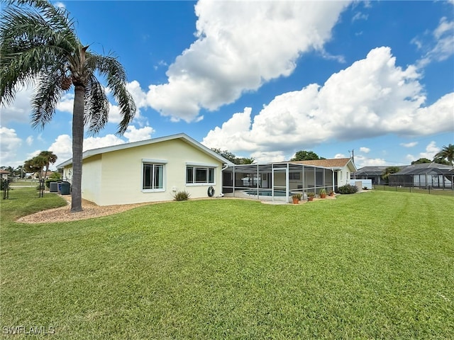 rear view of house featuring a yard, glass enclosure, and a swimming pool