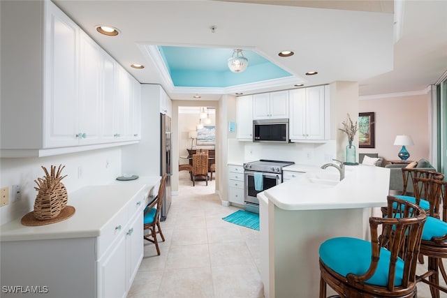 kitchen featuring white cabinetry, kitchen peninsula, stainless steel appliances, and a kitchen bar