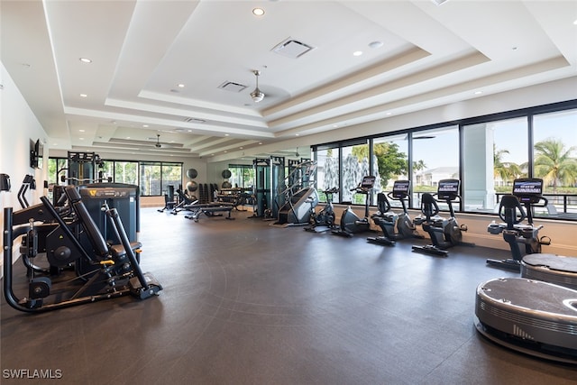 exercise room with ceiling fan and a raised ceiling