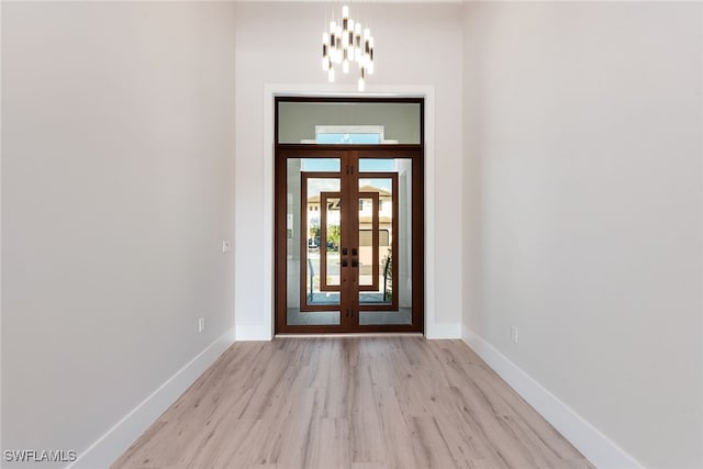 entryway with a notable chandelier, light hardwood / wood-style floors, and french doors