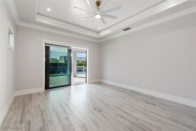 unfurnished room with a raised ceiling, ceiling fan, ornamental molding, and light wood-type flooring