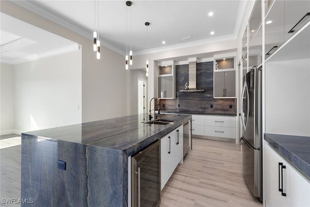 kitchen featuring wall chimney exhaust hood, stainless steel appliances, sink, pendant lighting, and wine cooler