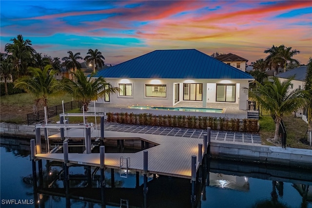 back house at dusk featuring a water view and a patio