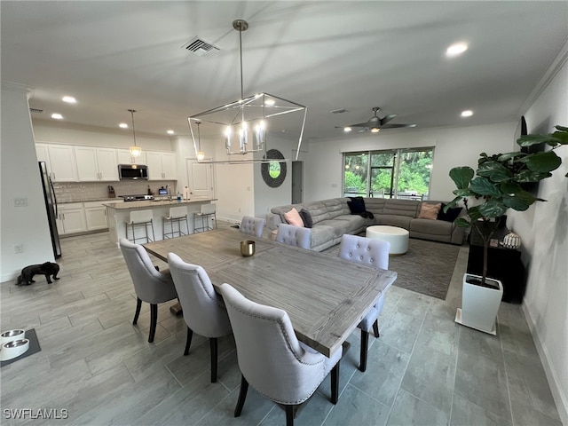 dining space featuring ceiling fan with notable chandelier, light hardwood / wood-style flooring, and ornamental molding