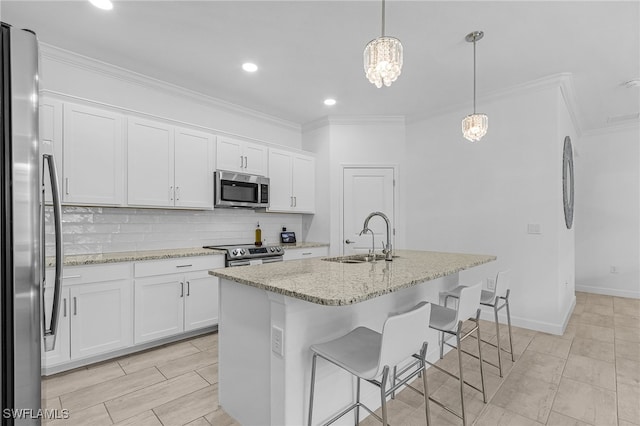 kitchen featuring stainless steel appliances, white cabinetry, pendant lighting, sink, and an island with sink