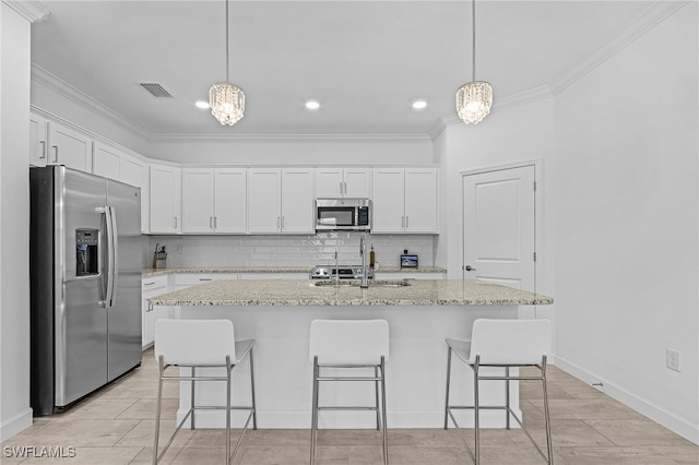 kitchen featuring stainless steel appliances, white cabinetry, ornamental molding, an island with sink, and decorative backsplash