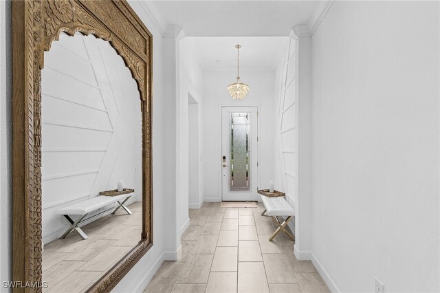 foyer entrance featuring an inviting chandelier and crown molding