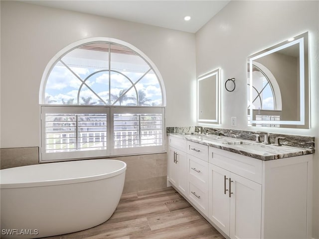 bathroom featuring vanity, a tub to relax in, a wealth of natural light, and hardwood / wood-style floors