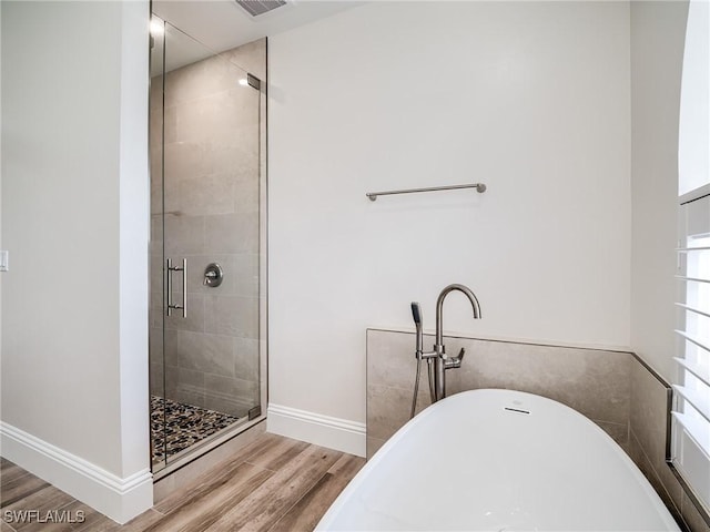 bathroom featuring wood-type flooring and shower with separate bathtub