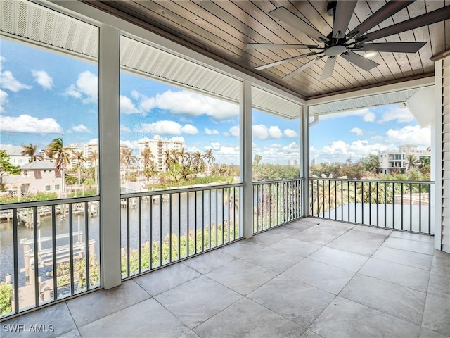 unfurnished sunroom featuring a water view, ceiling fan, and wooden ceiling