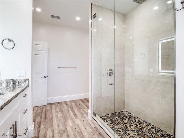 bathroom with wood-type flooring, a shower with door, and vanity