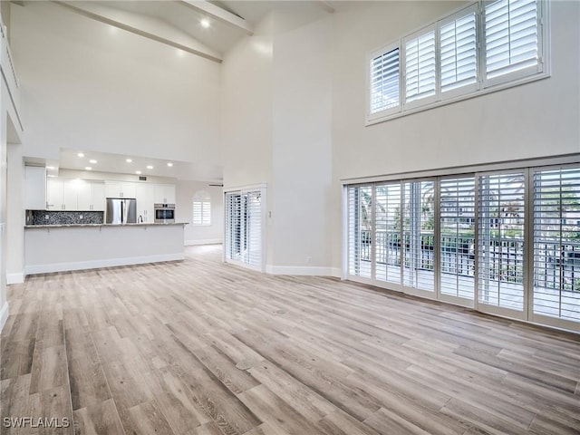 unfurnished living room with a towering ceiling and light hardwood / wood-style floors