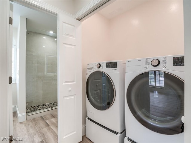 clothes washing area featuring washing machine and clothes dryer and light wood-type flooring