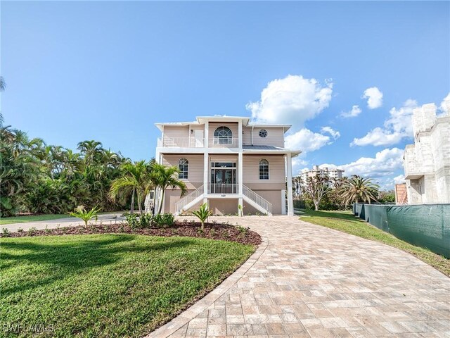 view of front of property with a front yard, a porch, a balcony, and a garage