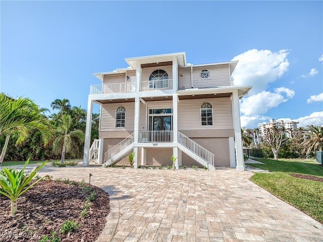 rear view of house with french doors, a balcony, and covered porch