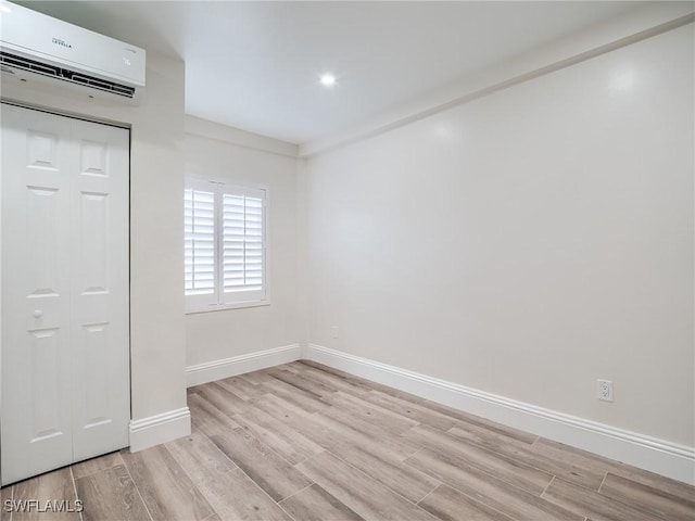 spare room with an AC wall unit and light hardwood / wood-style flooring