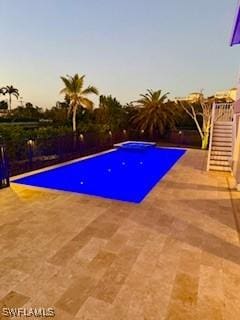 pool at dusk with a patio area