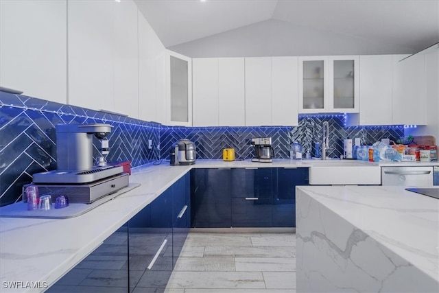 kitchen featuring decorative backsplash, white cabinetry, light stone countertops, and sink