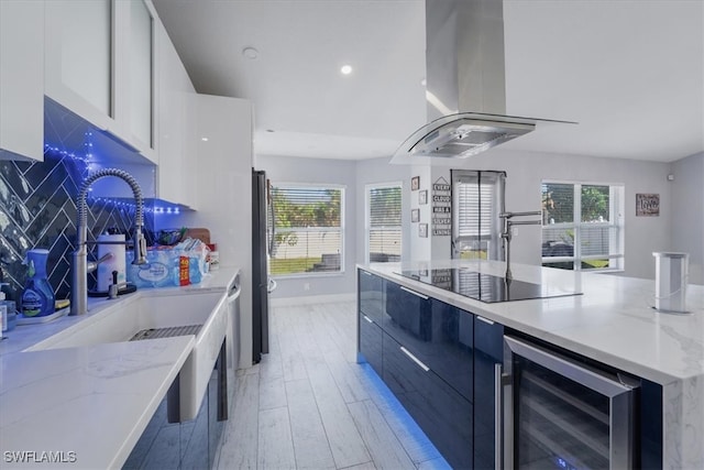 kitchen with wine cooler, white cabinets, island range hood, light hardwood / wood-style floors, and black electric stovetop