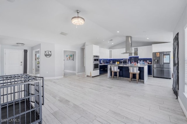 kitchen with appliances with stainless steel finishes, a breakfast bar, white cabinetry, extractor fan, and a center island