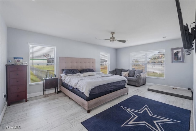 bedroom with ceiling fan, multiple windows, and light hardwood / wood-style floors