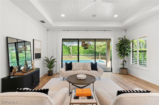 living room with light hardwood / wood-style floors, a raised ceiling, and wood ceiling