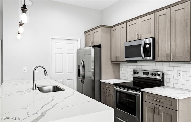 kitchen with stainless steel appliances, sink, backsplash, light stone countertops, and decorative light fixtures