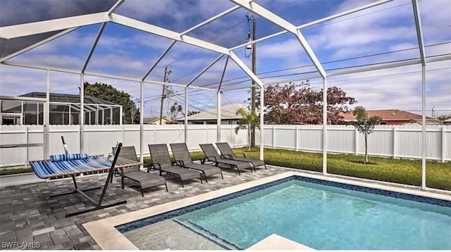 view of pool with glass enclosure and a patio area