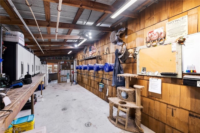 interior space with concrete floors, wood walls, a workshop area, and vaulted ceiling