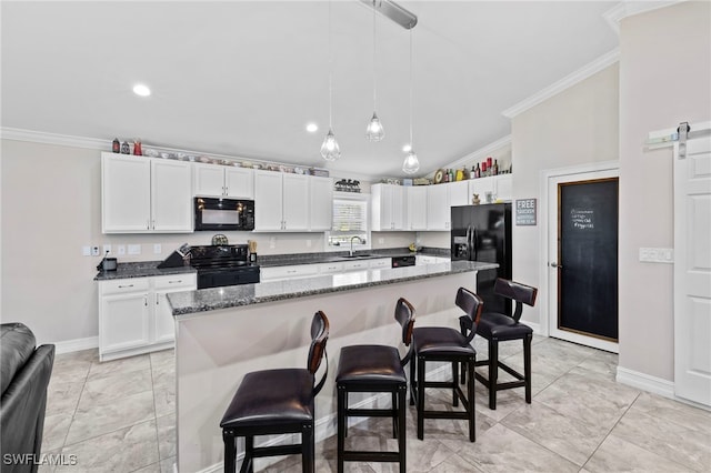 kitchen with black appliances, vaulted ceiling, a barn door, and a kitchen island